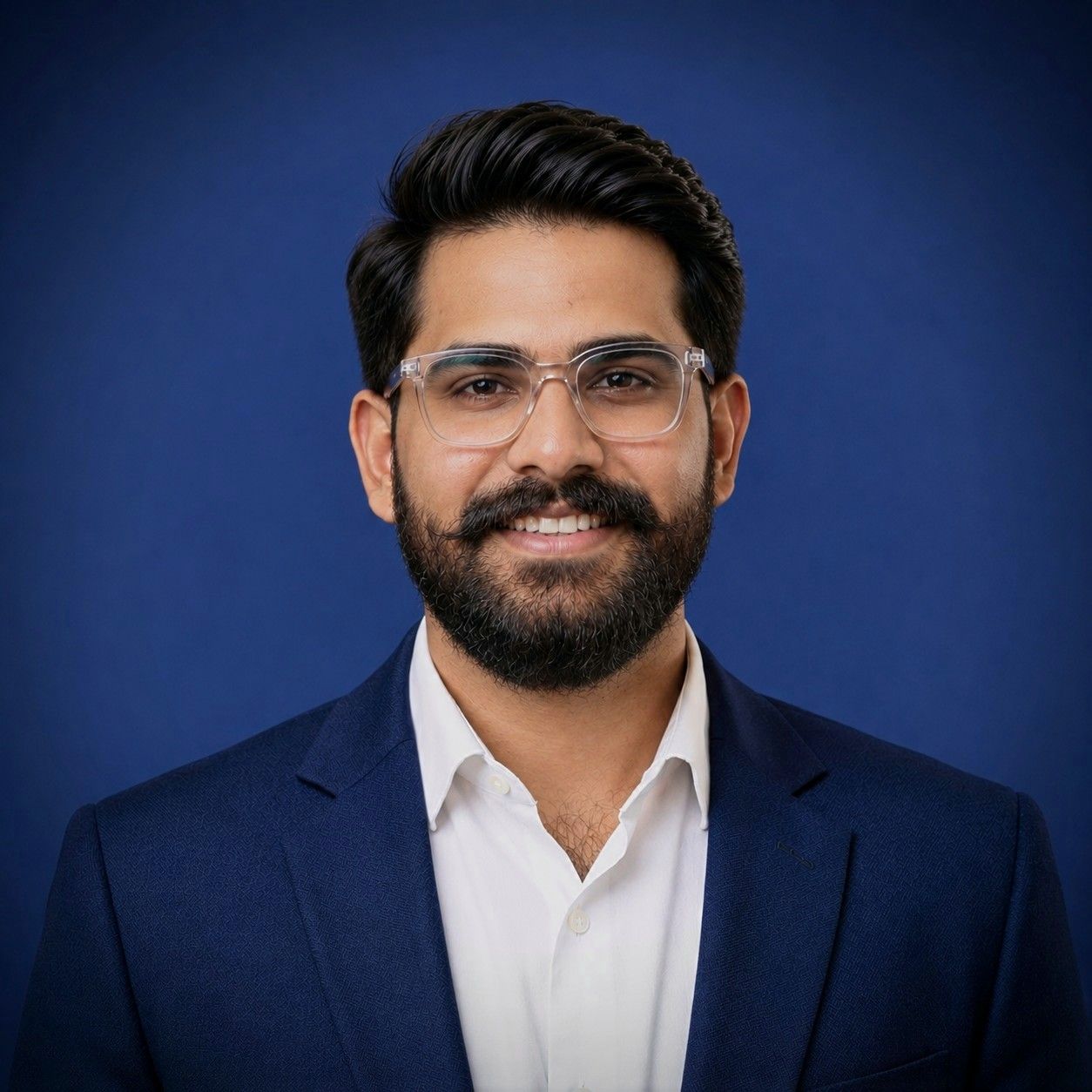 Portrait of Ali Zaman, Senior Business Analyst, in a navy blazer against a blue backdrop